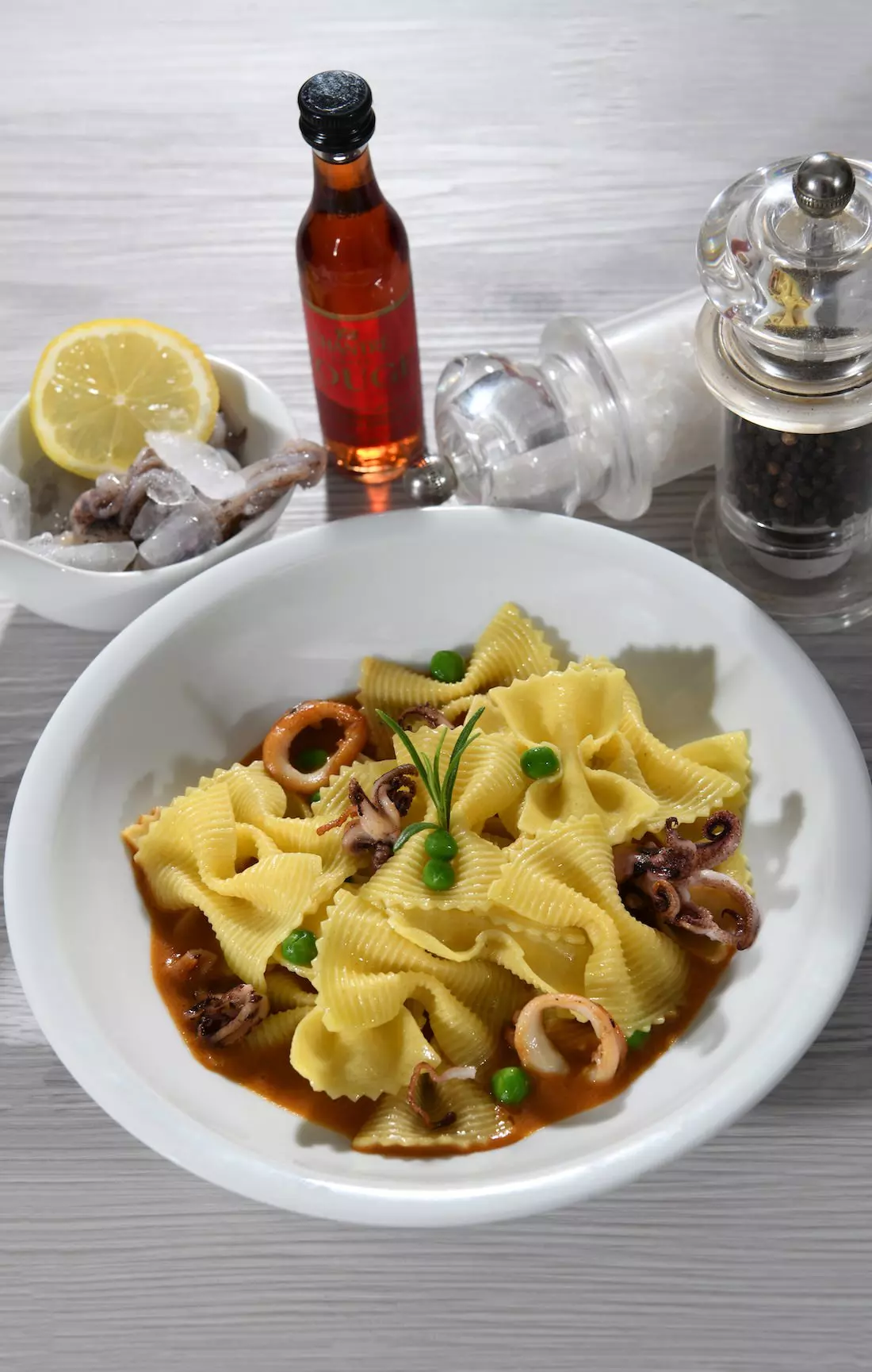 Nudeln (Farfalle) mit Tintenfisch (Calamari), Erbsen und Tomatensoße (Ragù).