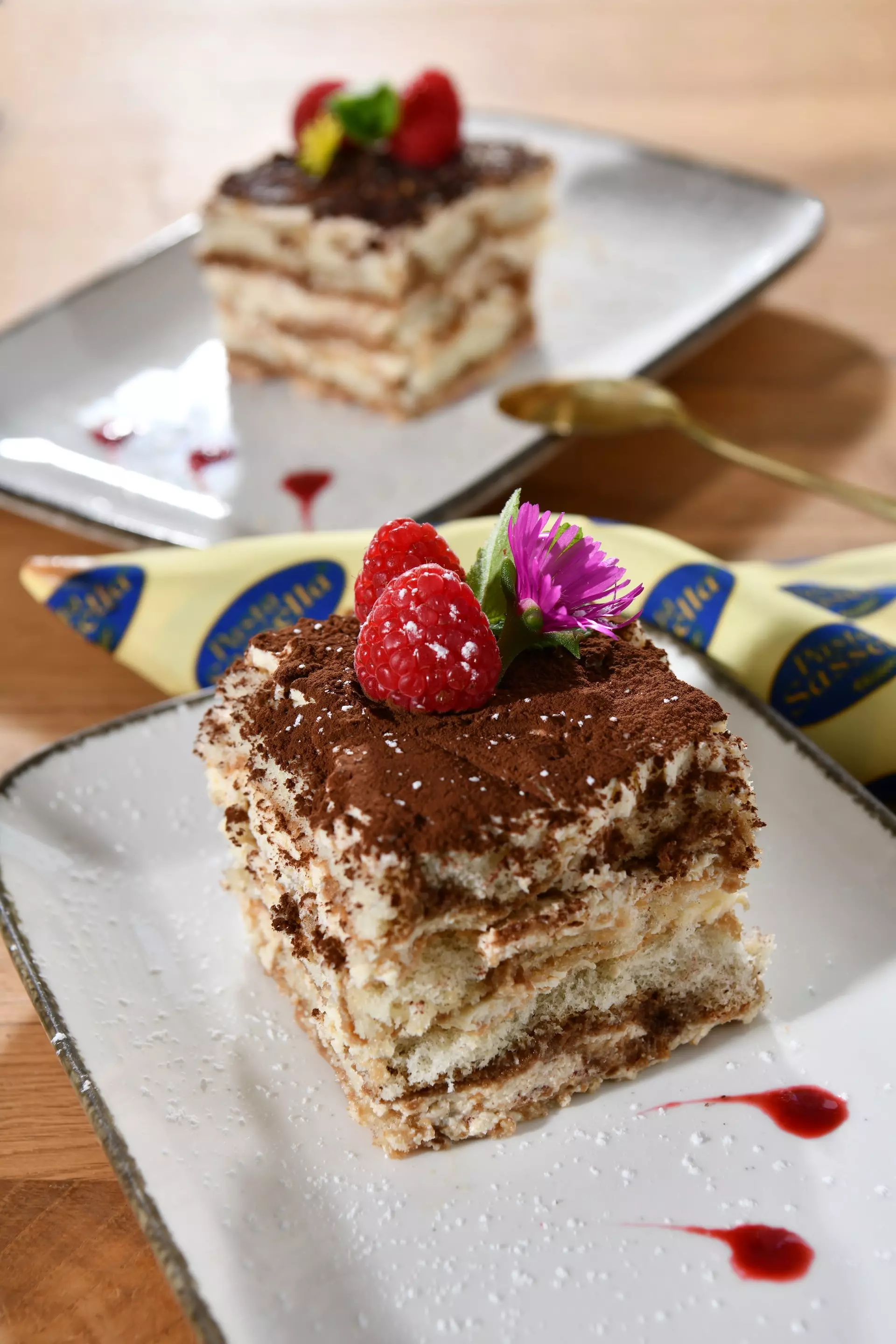 Tiramisu-Stück mit Himbeeren und Kakaopulver.